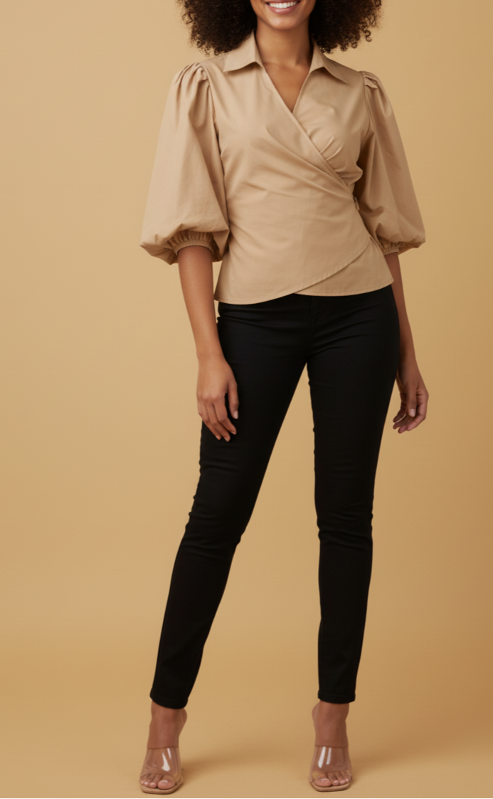 Woman wearing a beige blouse with puffed sleeves and black pants on a beige background