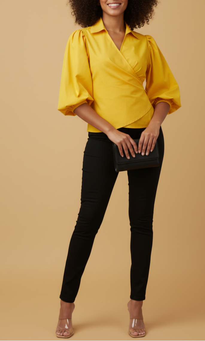 Woman wearing a yellow blouse with puffed sleeves and black pants against a beige background