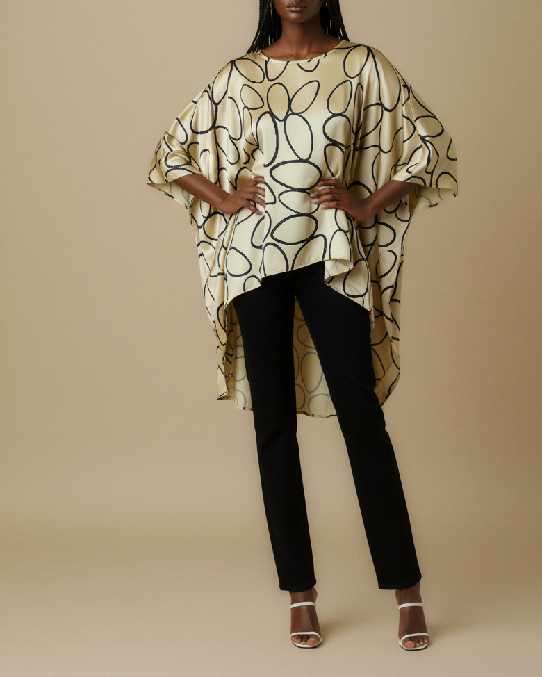 Front shot of a model wearing a gold high low top with black circles print with black pants against a beige background