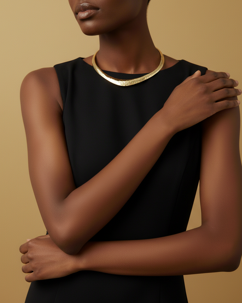 Model wearing a black dress with a gold choker against a beige background