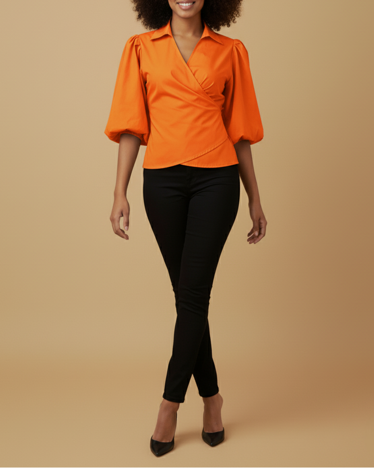 Front shot of a model wearing an orange wrap top with puffed sleeves and black pants on a beige background