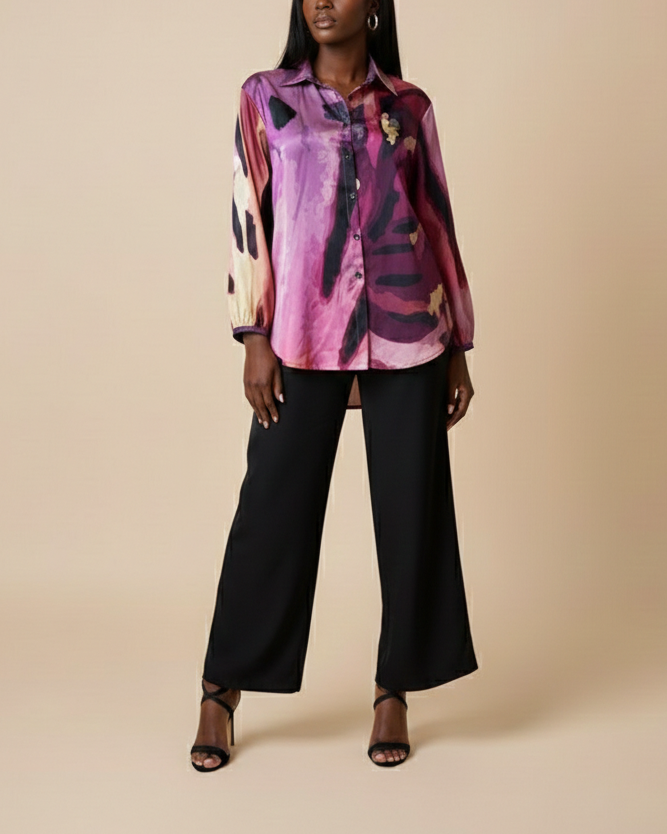 Front shot of a model wearing a colorful Peruvian lily floral printed button down shirt and black pants on a beige background.