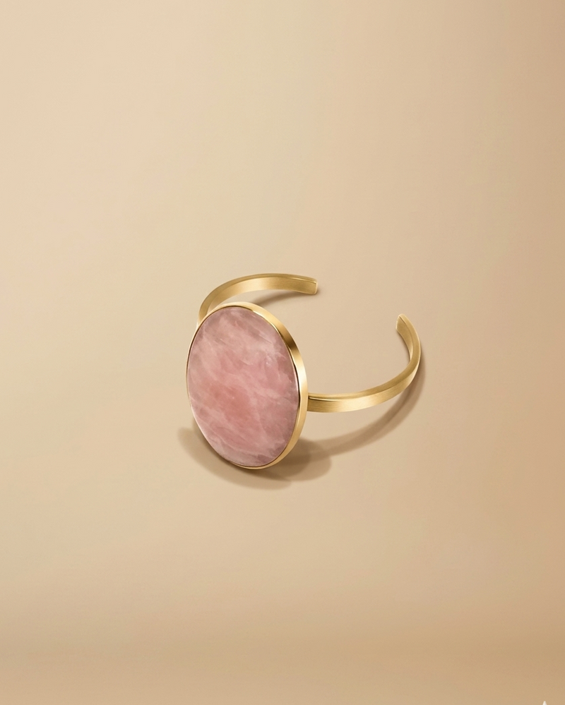 Gold bracelet with a rose quartz stone on a beige background