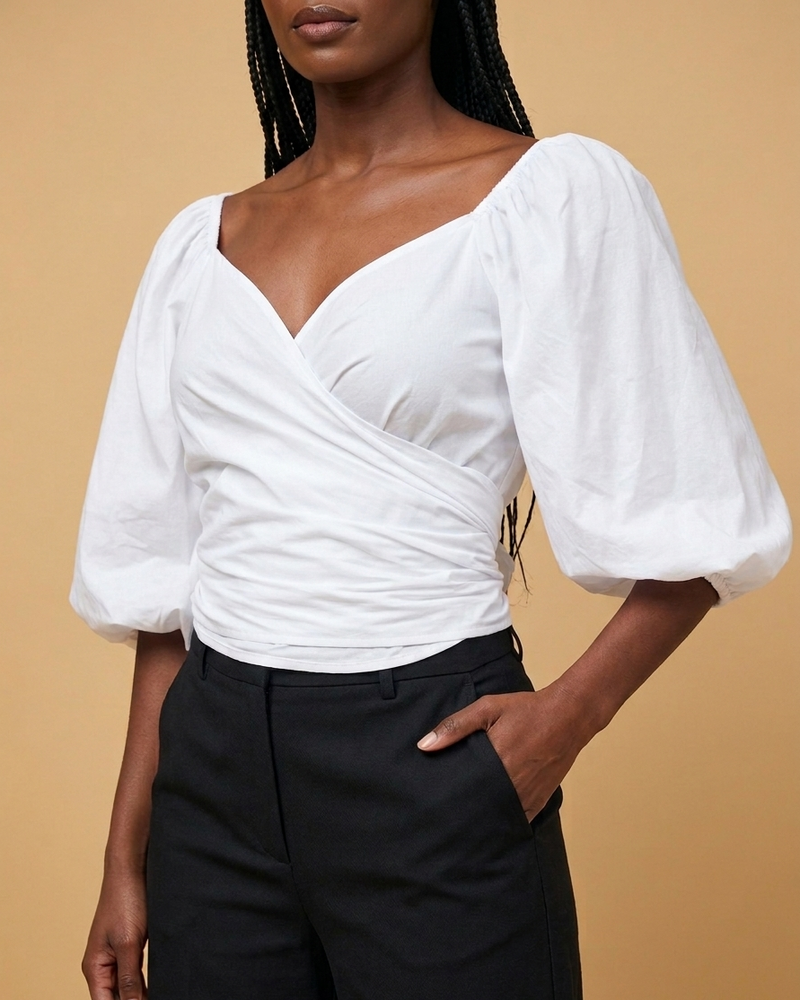 Front closeup shot of a model in a white wrap top and black wide leg pants.